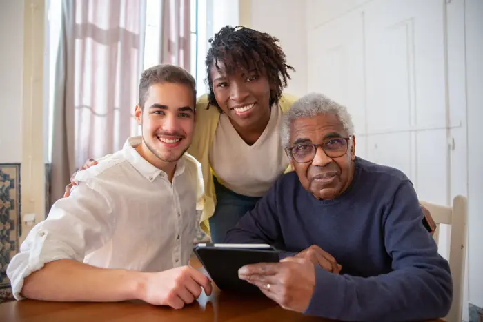 Stock photo: a caregiver and two people smiling together at home