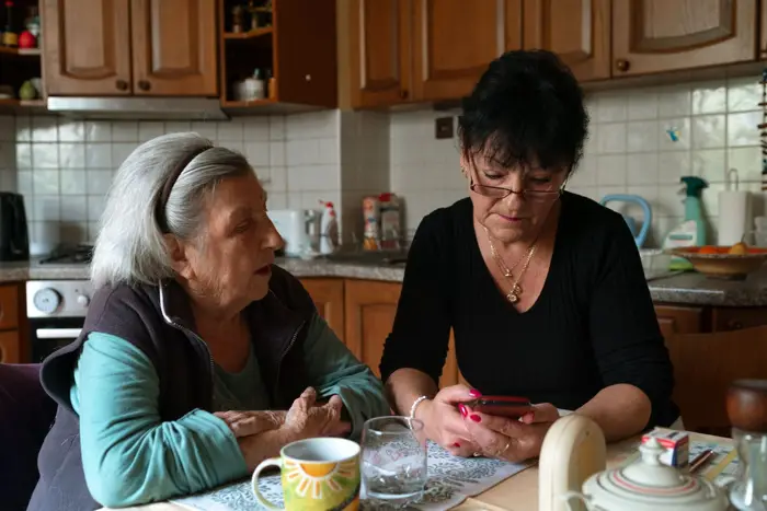 Stock photo: an older woman and a caregiver sharing tea at the kitchen table